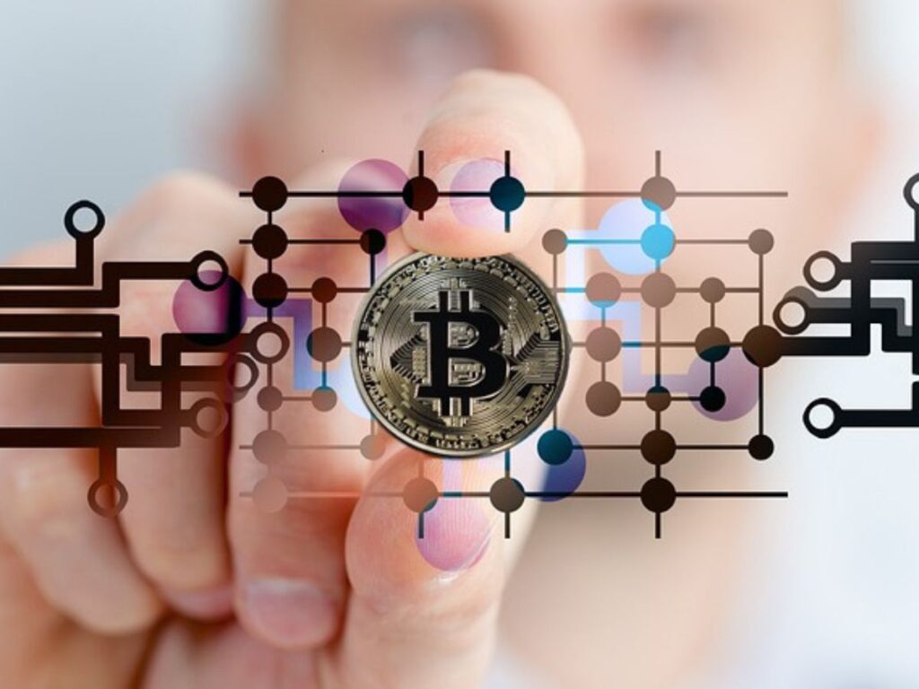 A hand holds up a Bitcoin; picture is overlaid with a tech inspired overlay