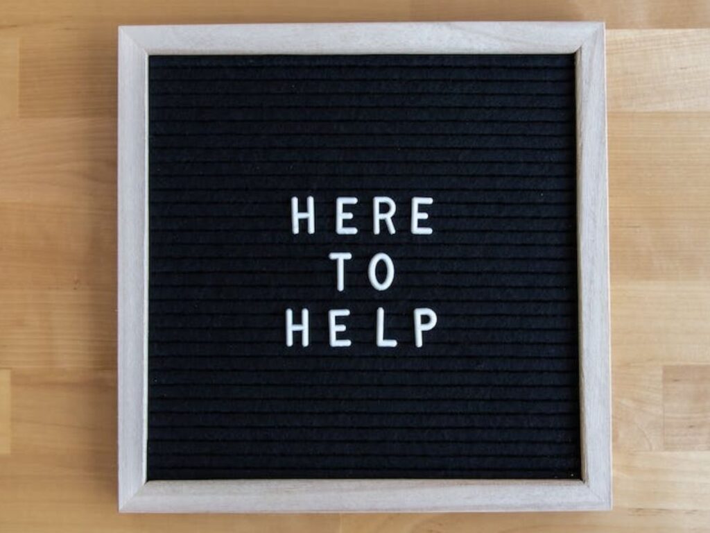 A sign on a wall that says “Here to help”