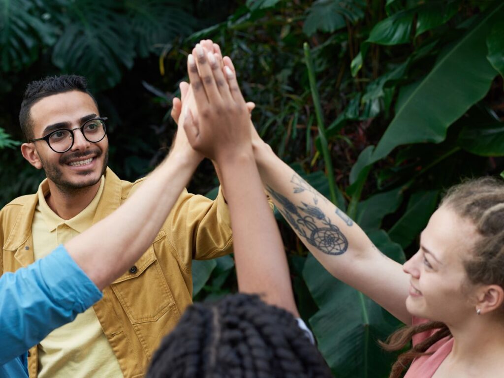 a group of diverse adventurers celebrate their teamwork with a group high five