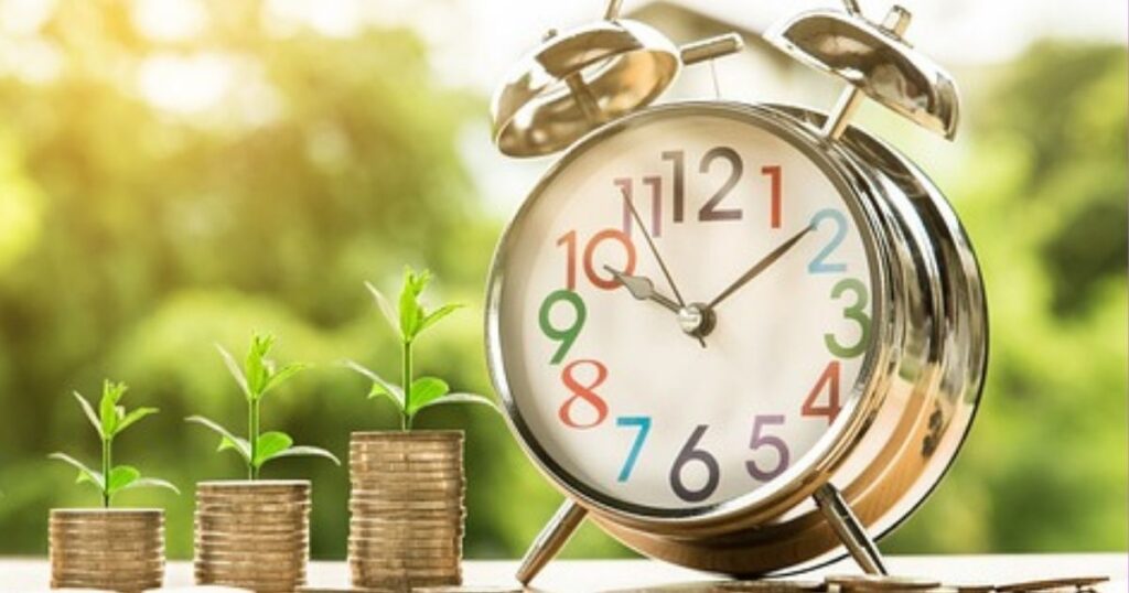 a colorful clock stands next to piles of coins that are growing young seedlings