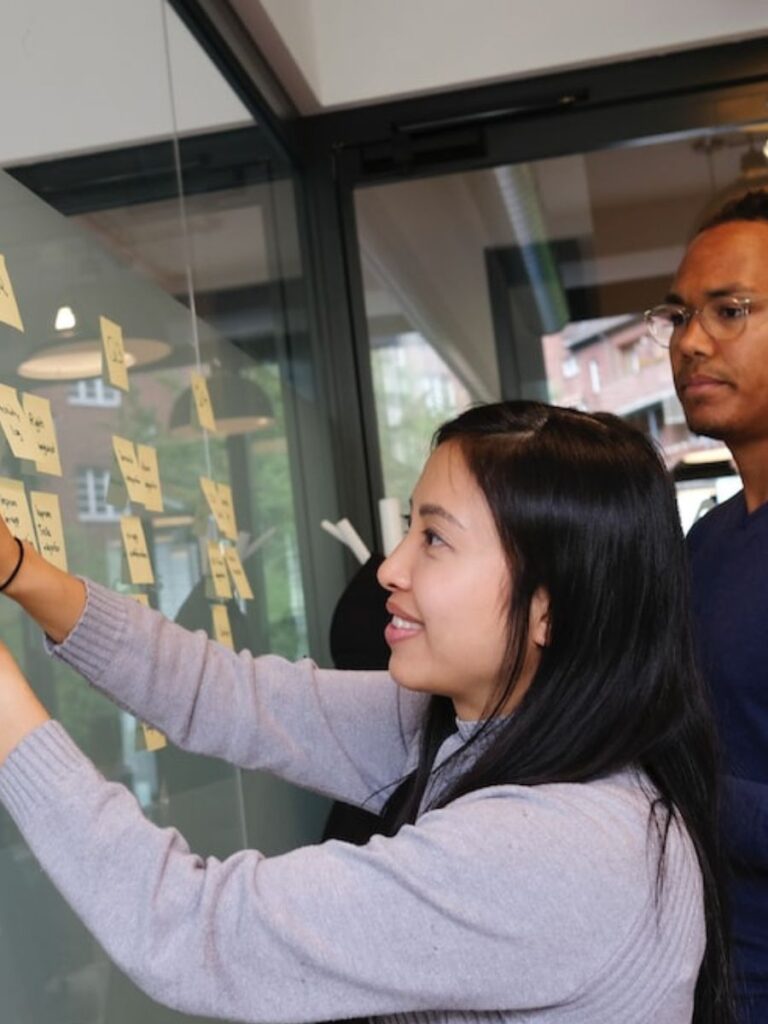 a woman’s face shines with hope as she works together with a partner on a whiteboard project