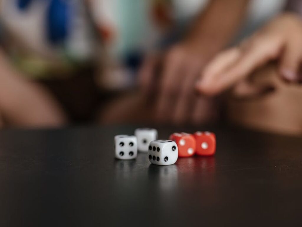 a set of five dice rolled on a table, two red with white pips and three white with black pips